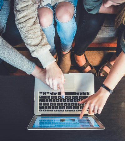 three person pointing the silver laptop computer