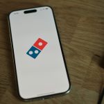 A white cell phone with a blue and red domino logo on it