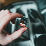 person holding black and red nintendo game cartridge