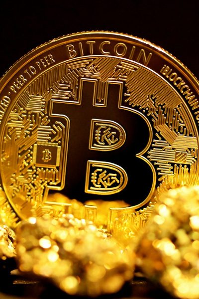 a bitcoin sitting on top of a pile of gold nuggets