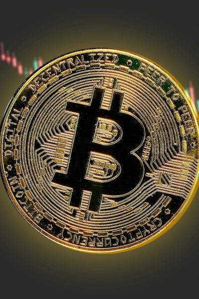 a bitcoin is shown in front of a stock chart