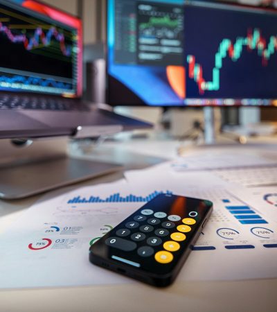 smartphone calculator on desk with financial charts behind