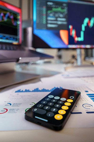 smartphone calculator on desk with financial charts behind