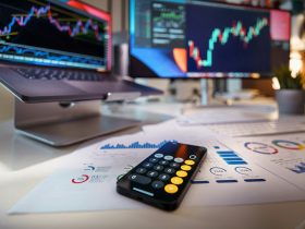 smartphone calculator on desk with financial charts behind