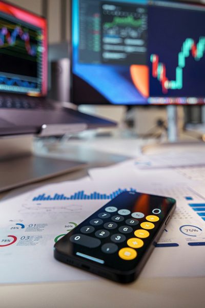 smartphone calculator on desk with financial charts behind